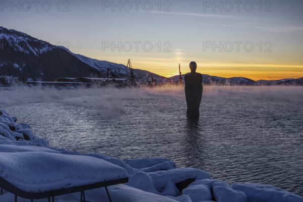 Statue (Havmannen) in the water at sunset with vapour mist, Mo i Rana, Norway