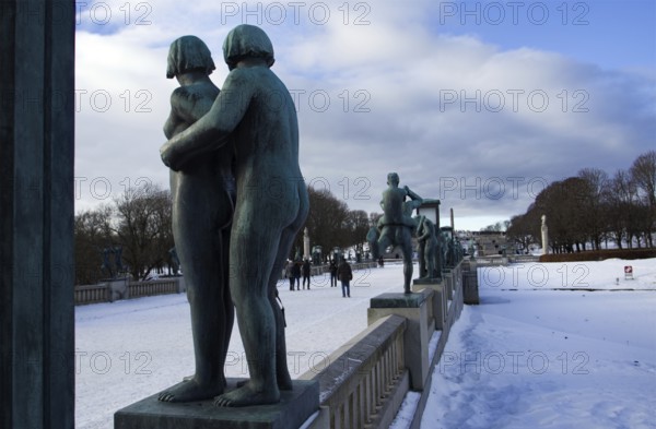 Sculptures on a snowy bridge, people walking, cold winter atmosphere, Vigeland sculpture park Oslo Norway