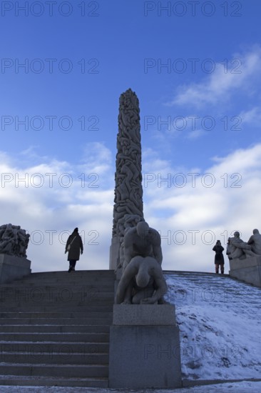Monolith and sculptures on snowy stairs. People standing and admiring, Vigeland Sculpture Park Oslo Norway