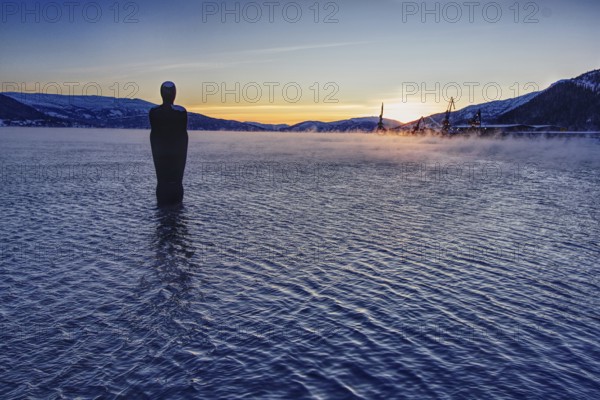 Sunset over a lake with a statue (Havmannen) in the water, Mo i Rana, Norway