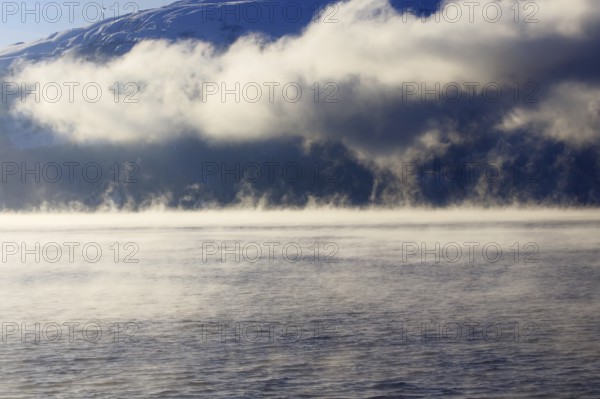 Clouds of fog over a lake with mountain scenery and clouds Norway