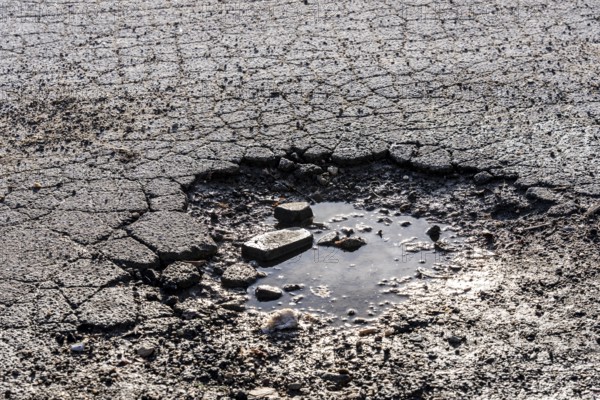 Pothole, asphalt surface, floor, with many small cracks, roadway, parking lot
