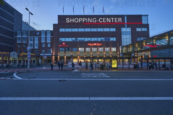 Sophienhof Kiel shopping center, commercial building, modern architecture, brick building, lantern, bus stop, bus lane, bus platform, waiting people and pedestrians as accessories, public transport, public transport, evening blue hour, blue evening sky, cumulus clouds, Sophienblatt street, Kiel, state capital, district-free city, Schleswig-Holstein, Germany