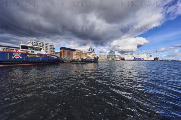 Kiel Fjord, port, pier, passenger ship, port and sea tug, ferry ship, general architecture, brick building, commercial building, water surface with small waves, blue sky, cumulus clouds, stratocumulus clouds, white and dark clouds, Kiel, state capital, district-free city, Schleswig-Holstein, Germany