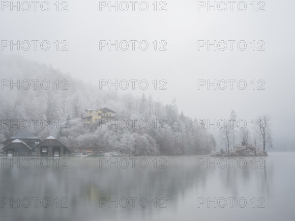 View across Königssee to boathouses, Christlieger island and frozen trees in fog, Schönau am Königssee, Berchtesgadener Land, Upper Bavaria, Bavaria, Germany