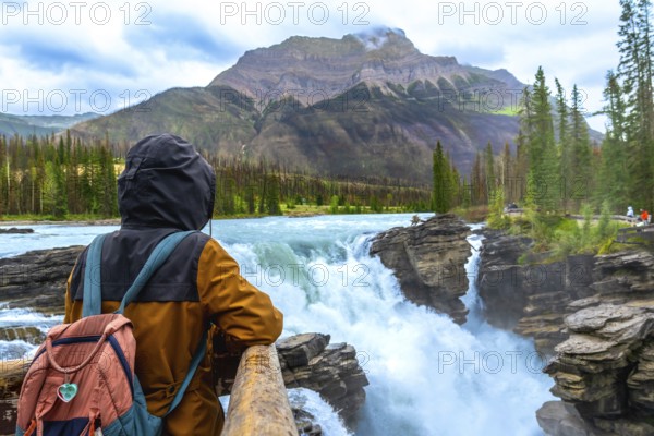 Backpacker enjoying the breathtaking view of athabasca falls cascading through the rugged landscape of jasper national park in the canadian rockies, a popular destination for outdoor enthusiasts