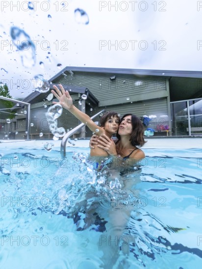 Mother and son are playing and splashing in a hot spring pool at miette hot springs in jasper national park, creating a moment of joy and connection amidst the beautiful natural surroundings