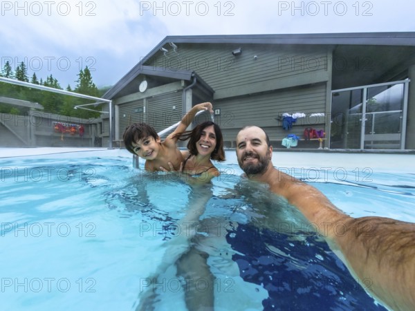 Happy family taking a selfie while bathing in miette hot springs, the hottest natural hot springs in the canadian rockies, located in jasper national park, alberta, canada
