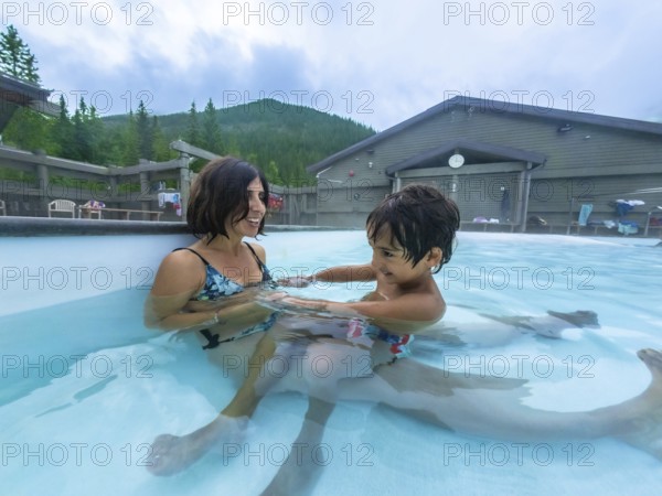 Mother and son are enjoying time together, playing in the warm, soothing waters of miette hot springs, surrounded by the stunning natural beauty of jasper national park, alberta, canada