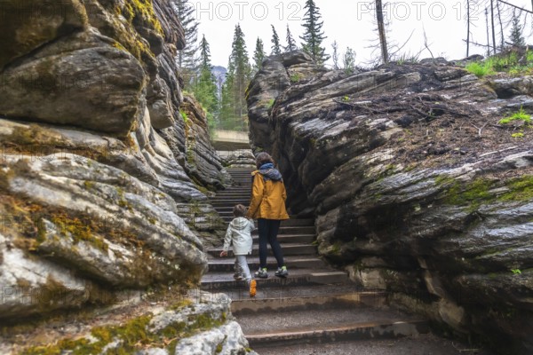 Mother and child walking up stairs among rocks and trees at athabasca falls in jasper national park, alberta, canada, enjoying a beautiful day in nature