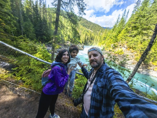 Family taking a selfie against the stunning backdrop of turquoise waters cascading over overlander falls in mount robson provincial park, british columbia, canada