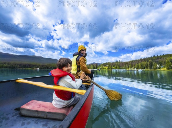 Father and son are paddling a canoe on beautiful maligne lake in jasper national park, alberta, canada, enjoying the stunning scenery of mountains and forests on a sunny day