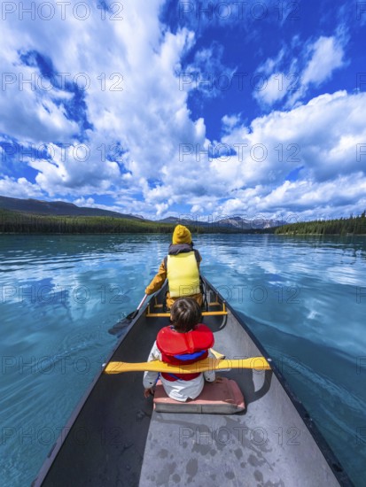 Tourists paddling a canoe on beautiful maligne lake in jasper national park, alberta, canada, enjoying a sunny day surrounded by stunning nature