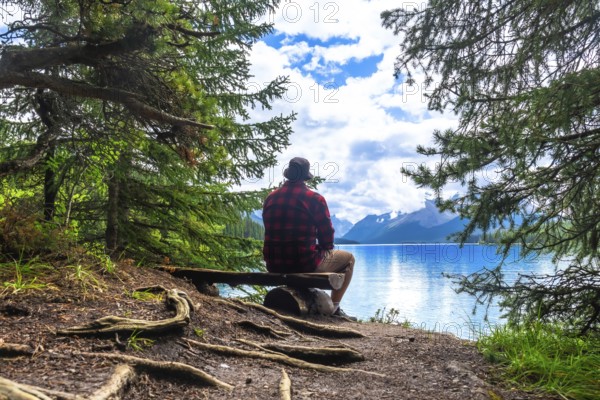 Tourist is enjoying the breathtaking view of turquoise maligne lake and its surrounding mountains in jasper national park, a renowned unesco world heritage site in the canadian rockies