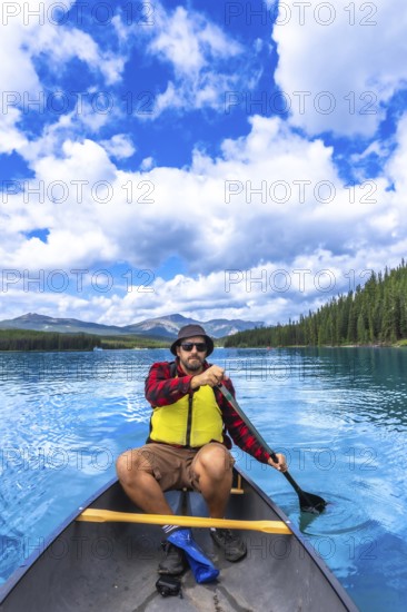 Tourist paddling a canoe in maligne lake under a beautiful cloudy sky, enjoying the turquoise water and surrounding nature of jasper national park in the canadian rockies