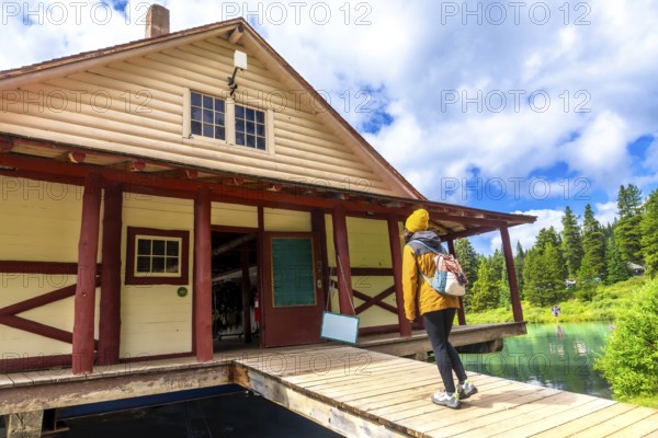 Hiker standing on the wooden pier of the boathouse at maligne lake enjoying the breathtaking view of the canadian rockies in jasper national park, alberta, canada