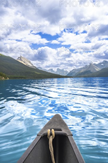 Canoe sailing on the turquoise waters of maligne lake with a stunning view of the canadian rockies in jasper national park, alberta, canada, under a cloudy blue sky
