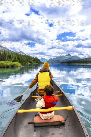 Tourists wearing life jackets are paddling a canoe on beautiful maligne lake in jasper national park, alberta, canada, enjoying a sunny day with blue sky and clouds