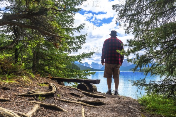 Tourist is enjoying the stunning scenery of turquoise maligne lake and surrounding mountains in jasper national park, a renowned unesco world heritage site