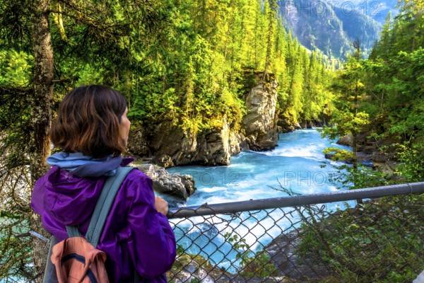 Female hiker enjoying the breathtaking turquoise waters of the fraser river cascading through the scenic canyon at overlander falls in mount robson provincial park, british columbia, canada