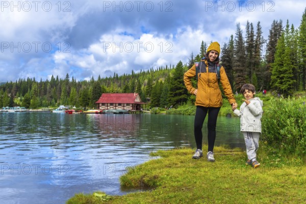 Mother and son holding hands, enjoying a scenic view of maligne lake boathouse in jasper national park, alberta, canada, surrounded by pristine nature and a tranquil atmosphere