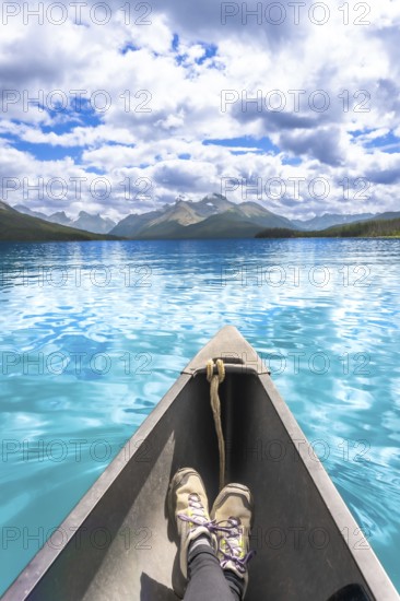 Tourist enjoys stunning view of turquoise water and mountain range while paddling canoe on maligne lake in jasper national park on a beautiful summer day
