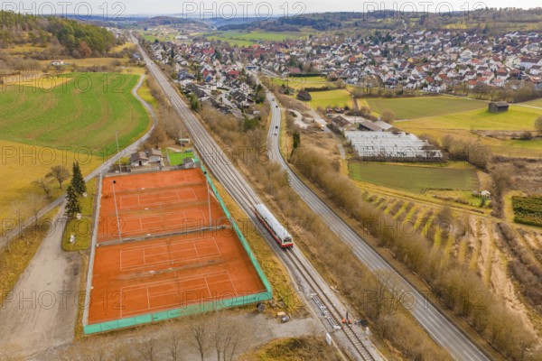Train line and tennis courts on the outskirts of the city in hilly countryside, historic event, first test run with a passenger train on the Hermann tracks, Hesse railway since 1988, Ostelsheim, Calw district, Germany