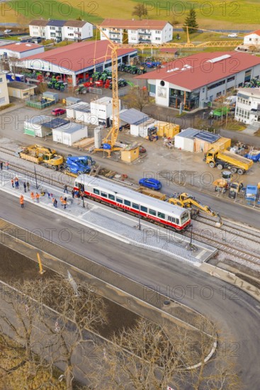 A train passes a large construction site with workers and a crane, historic event, first test run with a passenger train on the Hermann tracks, Hesse Railway since 1988, Calw district, Germany