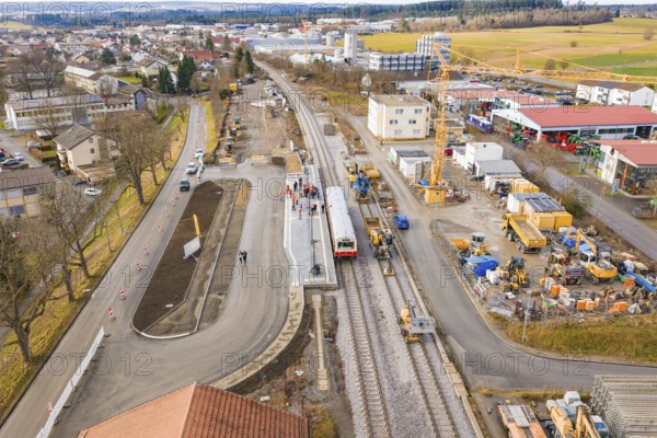 A few houses and a construction site at a municipal train station with train and construction work, historic event, first test run with a passenger train on the Hermann tracks, Hesse Railway since 1988, Calw district, Germany
