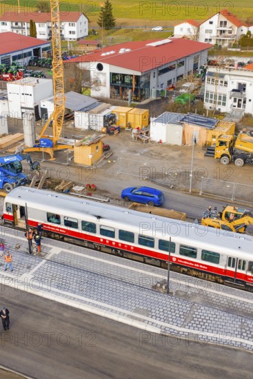 A train on a platform in the middle of a construction site with construction site vehicles and surrounding buildings, historic event, first test run with a passenger train on the Hermann tracks, Hesse Railway since 1988, Calw district, Germany