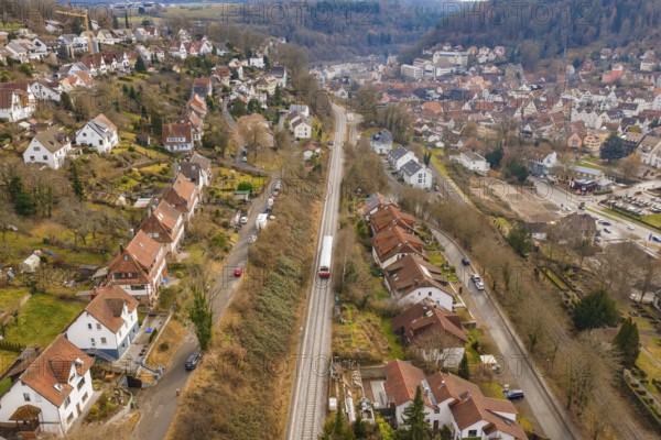 A train travels through a residential area that stretches along a wooded hill, historic event, first test run with a passenger train on the Hermann tracks, Hesse Railway since 1988, Calw, Calw district, Germany