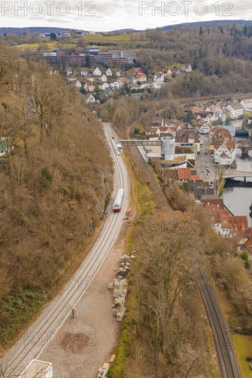 A train travels along tracks in a hilly urban landscape with numerous buildings, historic event, first test run with a passenger train on the Hermann tracks, Hesse Railway since 1988, Calw, Calw district, Germany