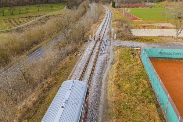 Aerial view of railway tracks next to a sports field with a passing train, historic event, first test run with a passenger train on the Hermann tracks, Hesse Railway since 1988, Calw district, Germany