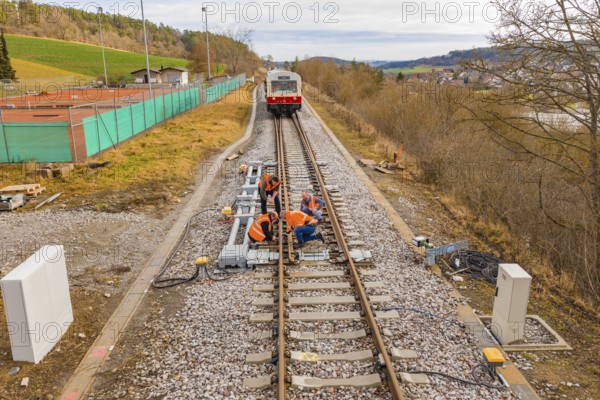 Construction workers working on railroad tracks with a train standing in the background, historic event, first test run with a passenger train on the Hermann tracks, Hesse Railway since 1988, Ostelsheim, Calw district, Germany