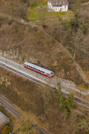 A train travels on a track through wooded hills in a wintry landscape, historic event, first test run with a passenger train on the Hermann tracks, Hesse Railway since 1988, Calw. Calw District, Germany