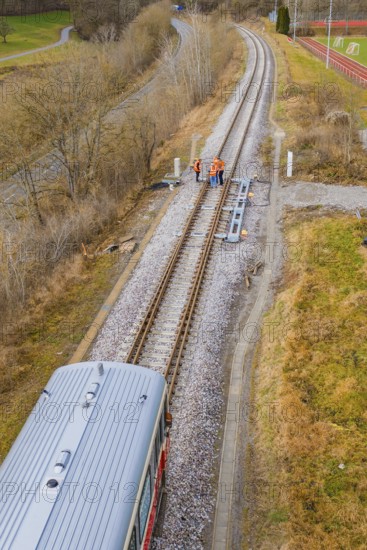 View along the railway tracks with a train and several construction workers on the rails, historic event, first test run with a passenger train on the Hermann tracks, Hesse Railway since 1988, Calw district, Germany