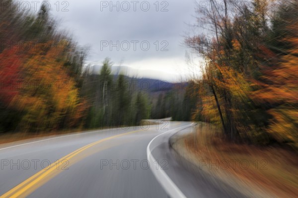 Winding country road through forest, autumn leaves, Indian summer, dark rain clouds, smudge effect, blur, symbolic photo, speed, Kancamagus Highway, White Mountain, New Hampshire, New England, USA