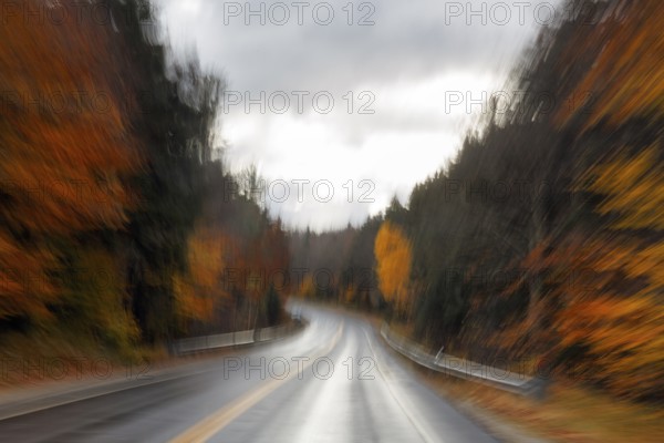 Winding, wet country road through forest, autumn leaves, Indian summer, dark rain clouds, smudging effect, blur, symbolic photo, speed, Kancamagus Highway, White Mountain, New Hampshire, New England, USA
