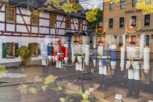 Window of a wooden nutcracker shop, reflecting a half-timbered house, health resort and toy village Seiffen, Ore Mountains, Saxony, Germany