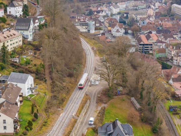 Train on railway line between town houses nestled in hilly, wooded landscape, historic event, first test run with a passenger train on the Hermann tracks, Hesse Railway since 1988, Calw, Calw district, Germany