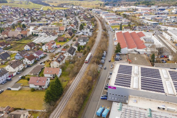 Train in a suburban landscape with residential buildings and industrial complexes, surrounded by rolling hills, historic event, first test run with a passenger train on the Hermann tracks, Hesse Railway since 1988, Althengstett, Calw district, Germany
