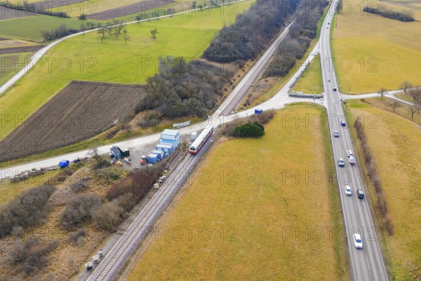 Train travels near a country road in a rural area with fields and vehicles, historic event, first test run with a passenger train on the Hermann tracks, Hesse Railway since 1988, Calw district, Germany
