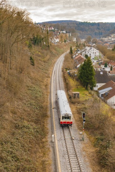 A single train travels on a railway line through a hilly residential area, historic event, first test run with a passenger train on the Hermann tracks, Hesse Railway since 1988, Calw, Calw district, Germany