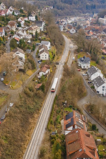 A train travels through a hilly urban landscape with numerous buildings, historical event, first test run with a passenger train on the Hermann tracks, Hesse railway since 1988, Calw, Calw district, Germany