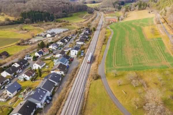A train travels through a village, surrounded by fields and forests, along the railway tracks, historic event, first test run with a passenger train on the Hermann tracks, Hesse Railway since 1988, Ostelsheim, Calw district, Germany
