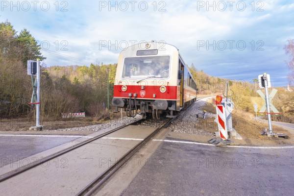 Train on a rail crossing, surrounded by trees, under a cloudy sky, historic event, first test run with a passenger train on the Hermann tracks, Hesse Railway since 1988, Calw district, Germany