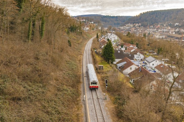 A train travels through an autumn landscape near a village with hills in the background, historic event, first test run with a passenger train on the Hermann tracks, Hesse Railway since 1988, Calw, Calw district, Germany