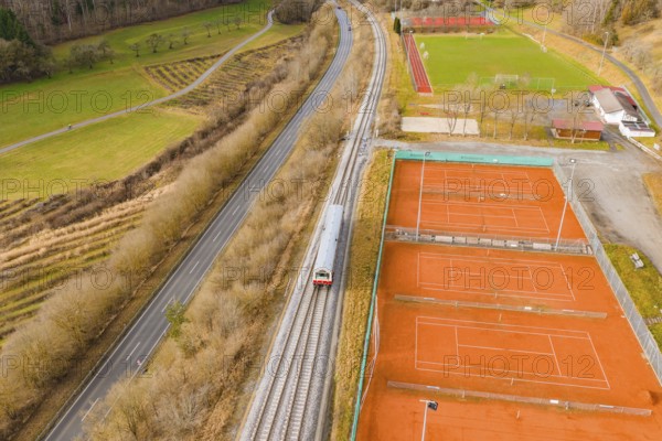 Train travels along tennis courts and green areas, autumn landscape with road and trees in the background, historic event, first test drive with a passenger train on the Hermann tracks, Hesse Railway since 1988, Ostelsheim, Calw district, Germany