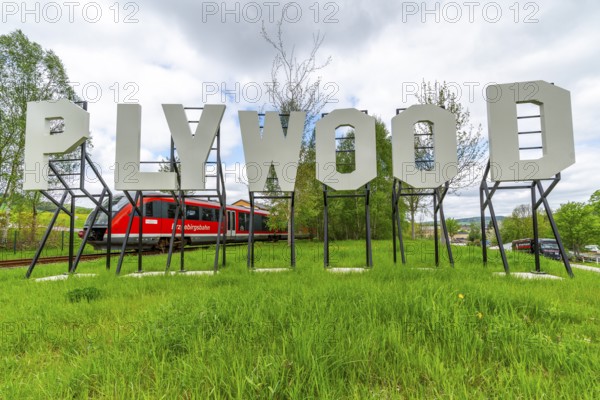 Sculpture, plywood art installation in the form of Hollywood lettering by artist Jay Gard, in the back a regional express from the Erzgebirgsbahn, Purple Path art and sculpture trail of the European Cultural Region around the cultural capital Chemnitz, Olbernhau, Ore Mountains, Saxony, Germany