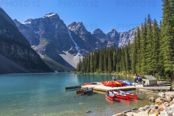 Colorful canoes tied to a wooden dock on turquoise waters of moraine lake, surrounded by the majestic peaks of the canadian rockies in banff national park